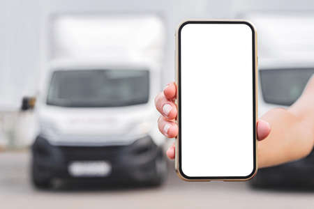 Smartphone mockup in female hand. Against the backdrop of trucks. Logistic conceptの写真素材