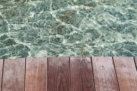 Wooden deck, tabletop on the surface of the water against the background of the poolの写真素材