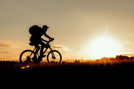 Silhouette of a man on a bicycle on a sunset background