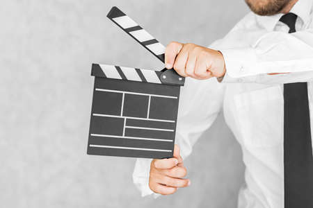 The director's clapperboard is in the hands of a man. On a light backgroundの写真素材