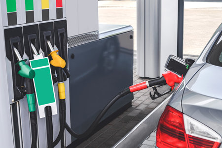 Refueling a car from a hose at a gas station. View of the dispenser with fuel pistolsの写真素材
