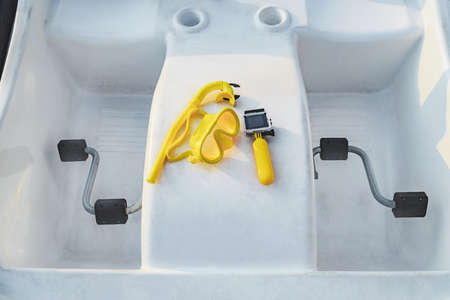 Waterproof action camera with yellow float and mask for snorkeling, diving. Against the background of a catamaran with pedals and a close-upの写真素材