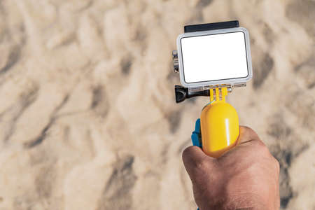 Close-up, Mockup of an action camera in a man's hand. beach sand in the backgroundの写真素材