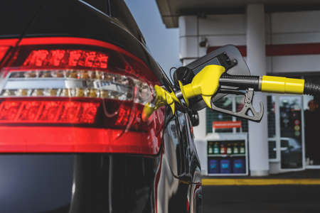 The gas station gun is inserted into the gas tank for refueling. close-up view