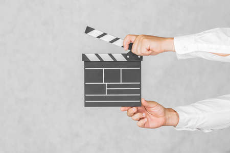 The director's clapperboard is in the hands of a man. On a light backgroundの写真素材