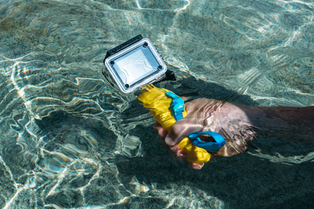 Action camera in the hands of a man on a warm sunny day. Against the backdrop of clear waterの写真素材
