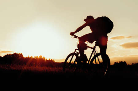 Silhouette of a man on a bicycle. Against the backdrop of a beautiful sky during sunsetの写真素材