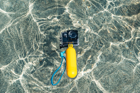 Close-up of a waterproof action camera with a yellow float in the water on the waves of the pool