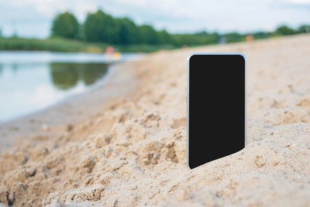 Close-up mockup of a smartphone on a sandy beach. against the backdrop of water and natureの写真素材