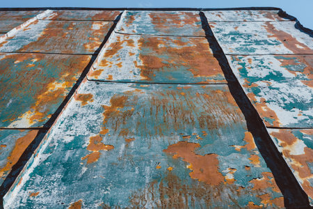 Close-up. Old metal roof. Background texture of the roofing surface of a weathered roof with peeling paint.の写真素材
