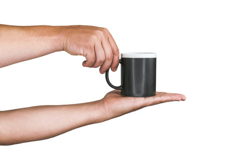 Close-up. Isolated black mug for coffee, tea in the hands of a man. On a white backgroundの写真素材