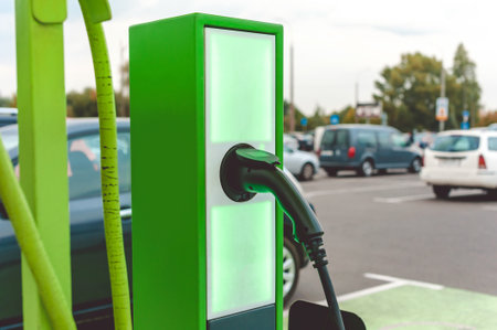Close-up Green electric station for charging vehicles. Parking background with cars outdoorsの写真素材