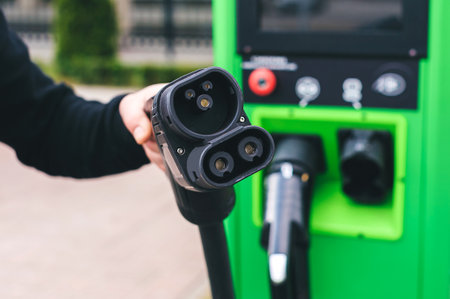car charger in the hands of a man against the background of a power station for charging cars in an...