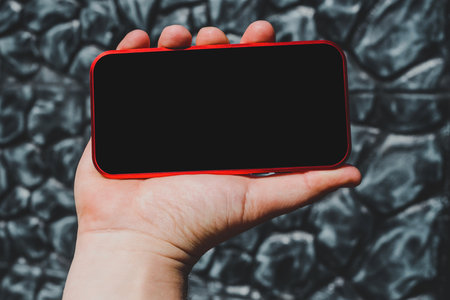 Mockup of a smartphone in a man's hand. Stone gray wall backgroundの写真素材