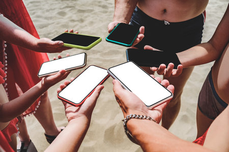 Mockups of mobile phones in the hands of a group of people. Sand background on the beach. The concept of travel and relaxationの写真素材