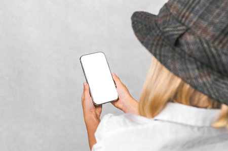 Close-up, mockup of a mobile phone in a person's hand. The background is light grayの写真素材