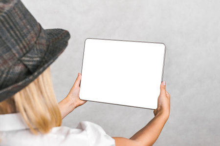 Close-up, frameless mockup of a digital tablet in a child's hand. The background is light grayの写真素材