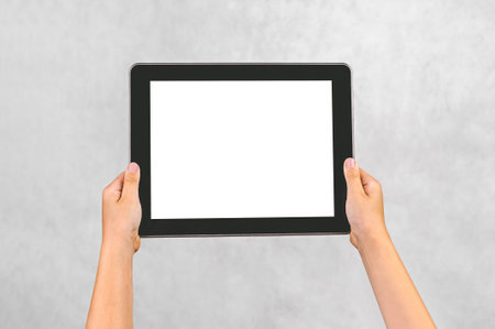 Close-up, mockup of a digital tablet in a child's hand. The background is light grayの写真素材