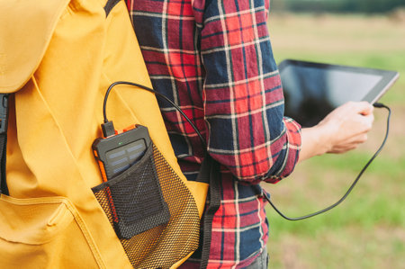 Power Bank in a hand, against the background of a digital tablet and green grassの写真素材
