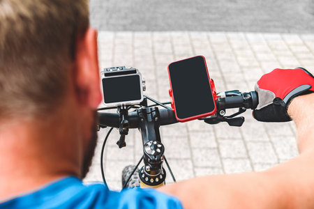 Smartphone and action camera on the handlebars of a bicycle. A man rides a bicycle