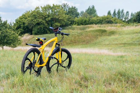 Yellow mountain bike in the foreground. Background of green grass, hills, trees and nature. Travel and active recreation conceptの写真素材