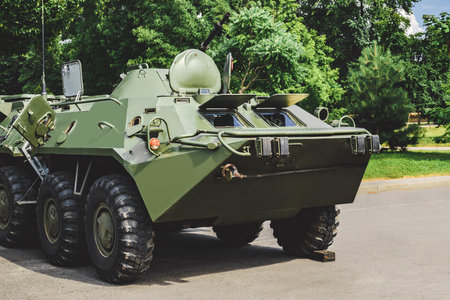 Military vehicle armored personnel carrier with camouflage coloring. Background of nature and trees