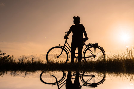 Silhouette of a cyclist with water reflection. Sunset backgroundの写真素材