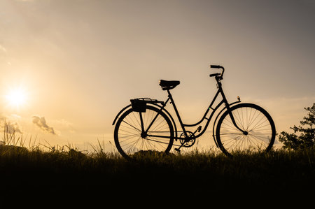 Silhouette of a bicycle or bike standing in a field outdoors, no people. Sunset background.の写真素材