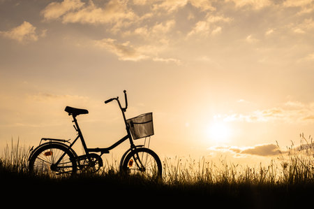 Silhouette of a bicycle or bike standing in a field outdoors, no people. Sunset background.の写真素材