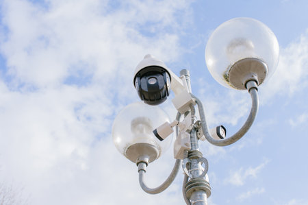 Surveillance camera on a street lamp. Against the background of the sky. AI people tracking technology concept CCTV security systemの写真素材
