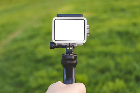 Close-up of the mockup of an action camera in the hand of a guy against a background of green grassの写真素材