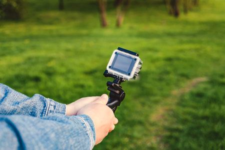Action camera on a tripod in the hands of a man. Green grass backgroundの写真素材