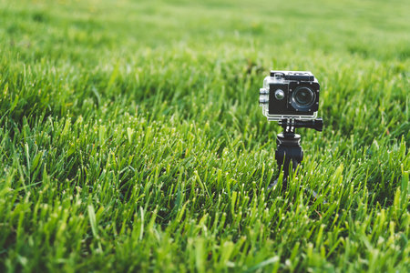 The action camera stands on a trepod in the green grassの写真素材