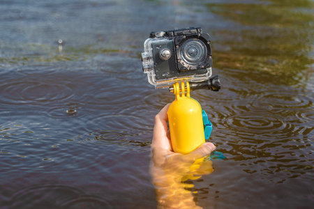 A waterproof action camera with a yellow float in the hand of a young girl. Close-up water...