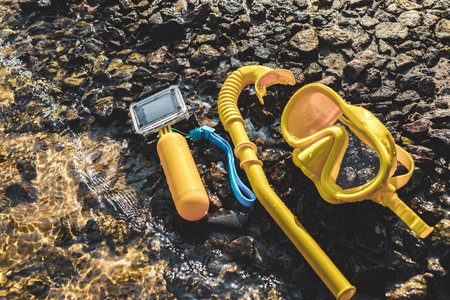 Waterproof action camera with a mask and snorkel on a rocky shore near the water. Swimming ban conceptの写真素材