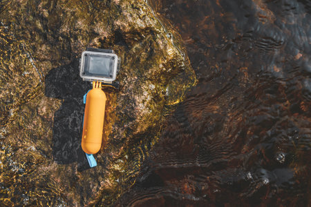 The action camera lies face up on a rock in the water. Time for hobbies and outdoor activitiesの写真素材