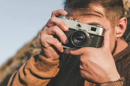 Close-up man holding retro camera taking pictures while sitting on haystacksの写真素材