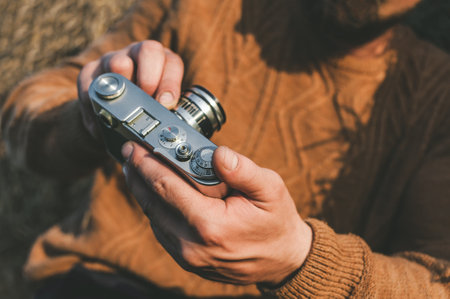 Close-up of a retro camera in a man's hand, photographing a selfie. Hay bale backgroundの写真素材