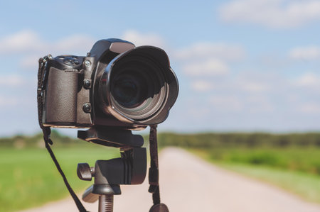Close-up of a camera on a tripod. Background of the road on the field
