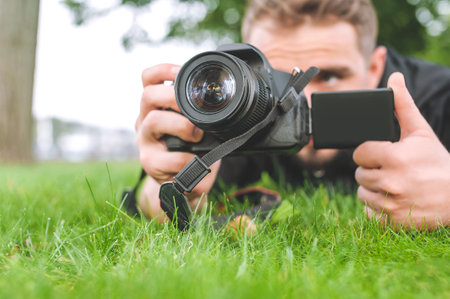 Close-up. A man with a camera takes pictures on the green grassの写真素材
