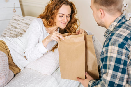 Happy woman looking into paper bag with man indoorsの写真素材