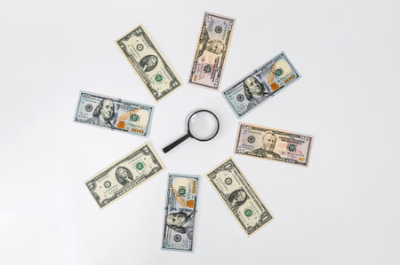 Magnifying glass on the background of dollars on a white tableの写真素材