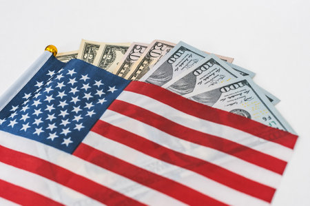 Money dollar bills with the American flag on a white backgroundの写真素材