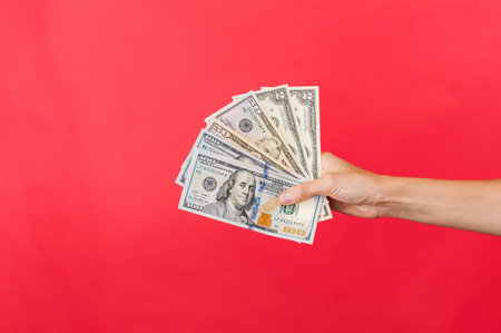 Money US dollars in a woman's hand. On a red background