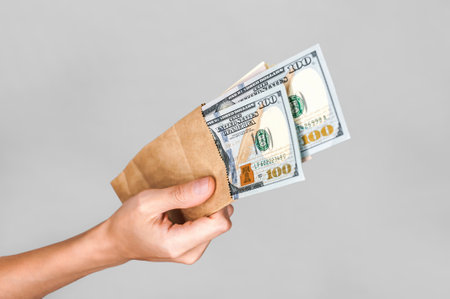 American dollars in a paper bag in a girl's hand. On a white backgroundの写真素材