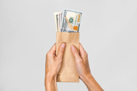 American dollars in a paper bag in the hands of a girl. On a white backgroundの写真素材