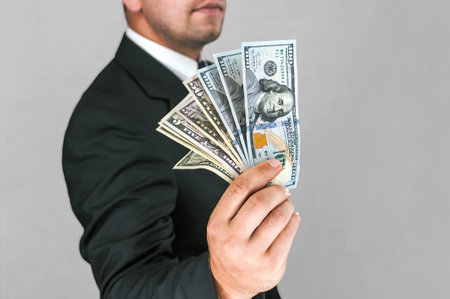 Close-up, American dollars money in the hand of a business man. White and gray backgroundの写真素材