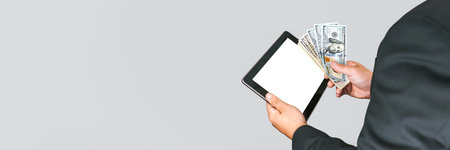 Banner, A man in a business suit holds a tablet mockup with money on a gray and white backgroundの写真素材