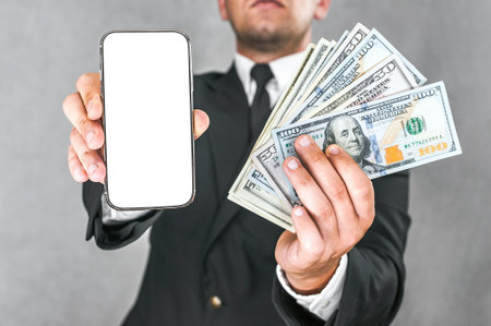 Close-up mockup smartphone with American dollars in the hands of a businessman in a business suit. on a light gray backgroundの写真素材