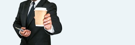 Banner, Close up cardboard disposable glass of takeaway coffee or tea with American dollars in businessman hands on gray and white backgroundの写真素材